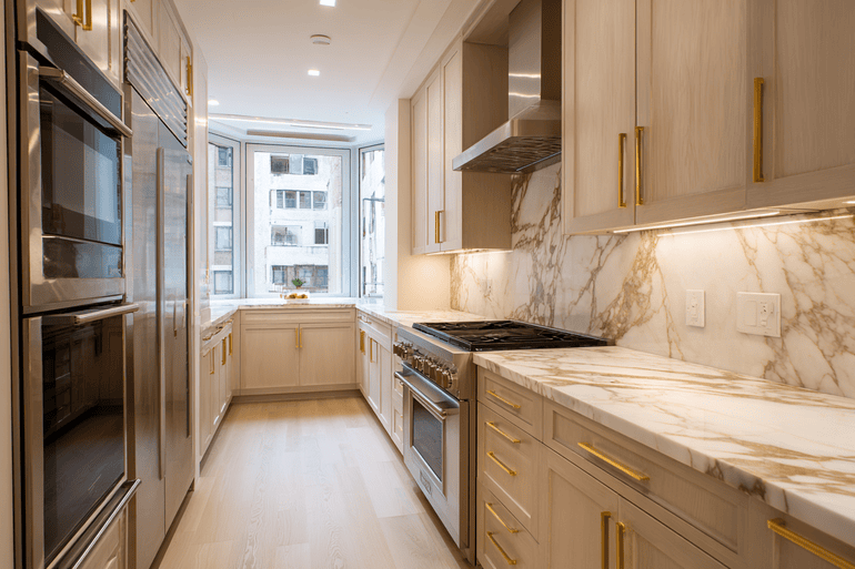 NYC loft kitchen renovation showing exposed original wall construction beside finished marble and white oak cabinetry