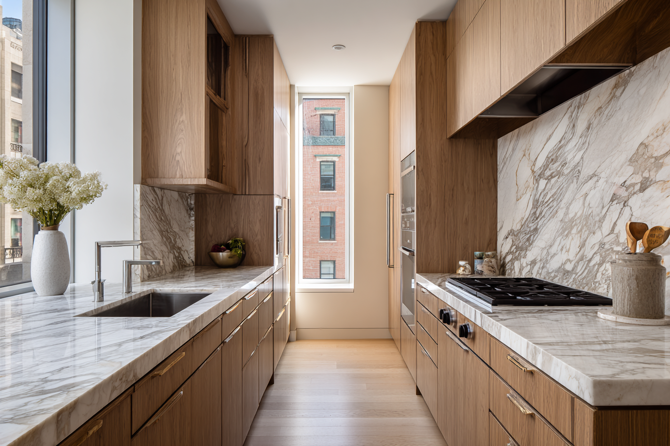 Custom NYC loft kitchen with precisely aligned cabinetry and natural stone countertops, showing the finish quality of coordinated renovation management