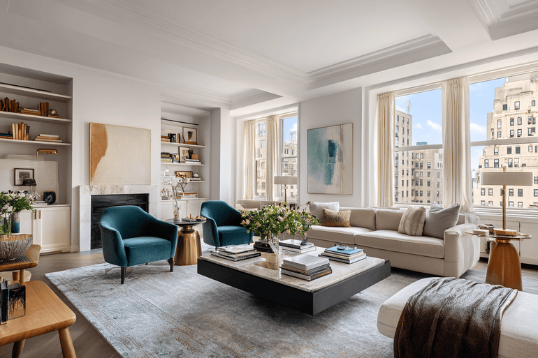 Sunlit NYC loft living room with exposed beams, bouclé sofa, and warm neutral palette with a pop of burnt-orange color